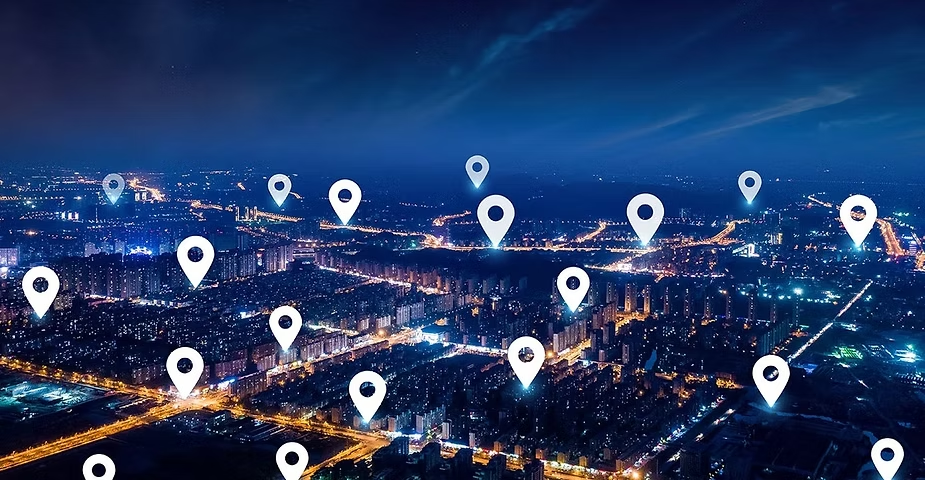 Aerial night view of a lit-up city with location pin icons overlaid across the skyline