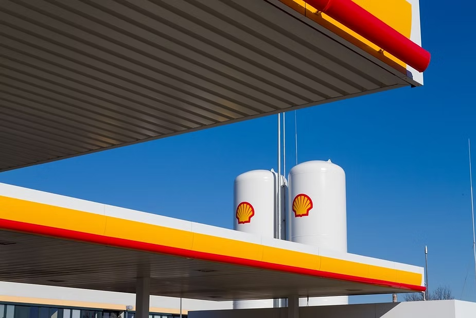 Shell fuel storage tanks and canopy signage with the shell logo against a blue sky at a gas station