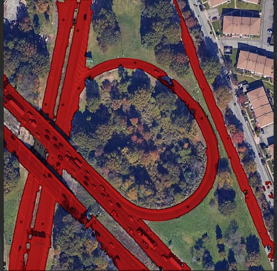 Clean red road segmentation result on a satellite highway loop and interchange near residential houses, following the road cleanly with point prompts